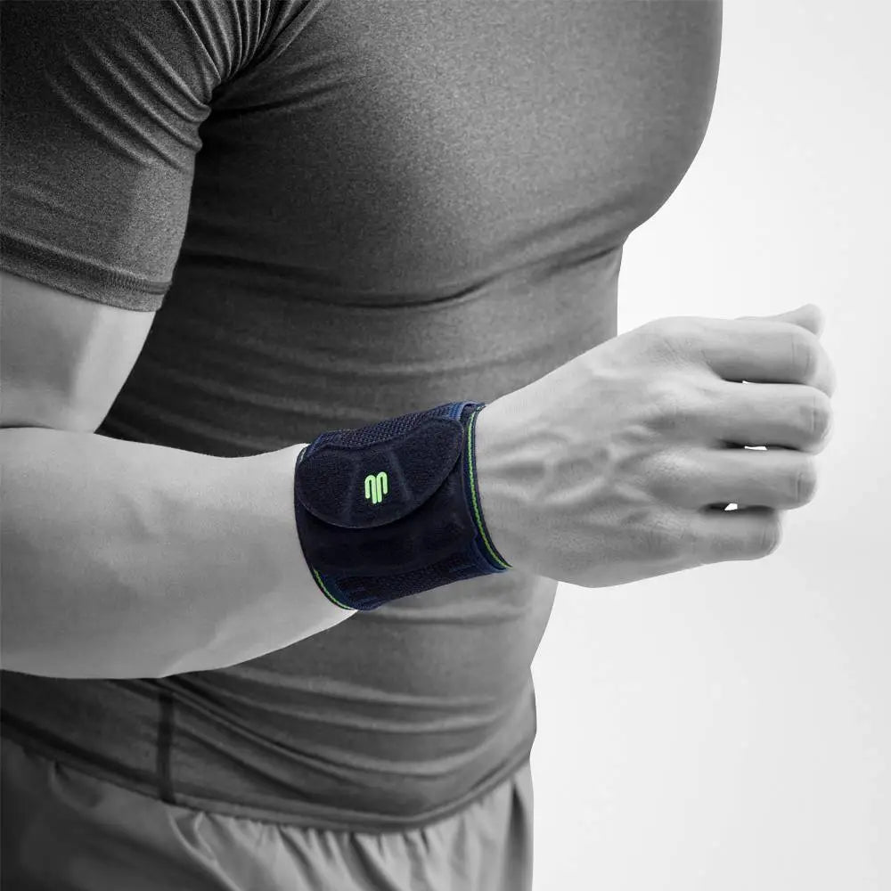 Die Abbildung zeigt den Bauerfeind Sports Wrist Strap, eine flexible Handgelenkbandage, die speziell für sportliche Aktivitäten entwickelt wurde. Die Bandage besteht aus atmungsaktivem, hautfreundlichem Material und verfügt über ein individuell einstellbares Gurtsystem, das gezielten Druck auf das Handgelenk ausübt, um es zu stabilisieren und zu entlasten. Der Wrist Strap hilft, Schmerzen und Überlastungen vorzubeugen, indem er die Gelenkführung verbessert und das Handgelenk unterstützt.