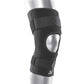 Das Bild zeigt die BioSkin Hinged Knee Sleeve Wraparound, eine stützende Kniebandage mit seitlichen Stäben zur Stabilisierung des Kniegelenks. Die Bandage besteht aus einem leichten, atmungsaktiven Material und ist so gestaltet, dass sie das Knie umschliesst und mit Klettverschlüssen individuell angepasst werden kann. 