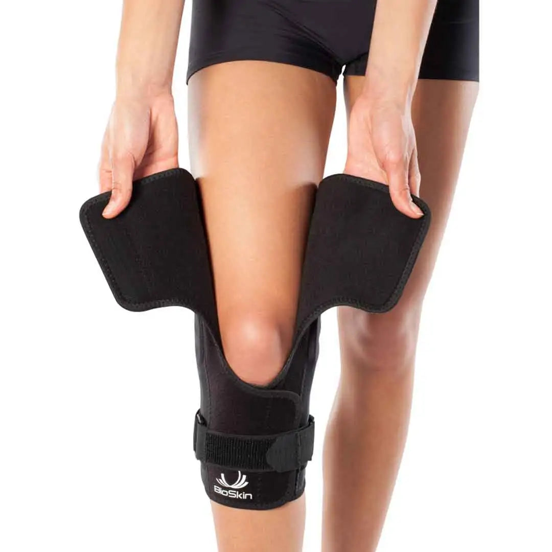 Das Bild zeigt die BioSkin Q Brace CrossFire Kniebandage, eine schlanke und ergonomisch Bandage, die das Knie stabilisiert. Die offene Patellaposition entlastet den Druck auf die Kniescheibe, während das Kreuzgurtsystem seitliche Stabilität gewährleistet.